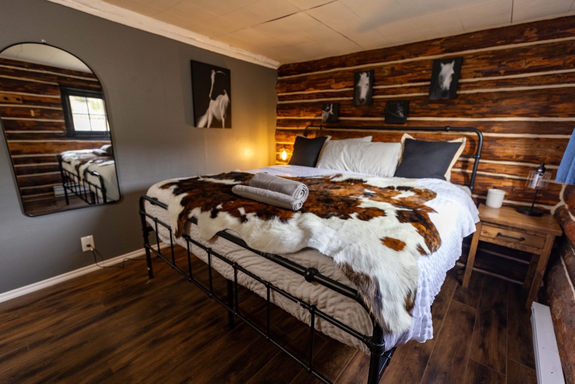 King bedroom inside Cabin 3 with cowhide throw and log walls